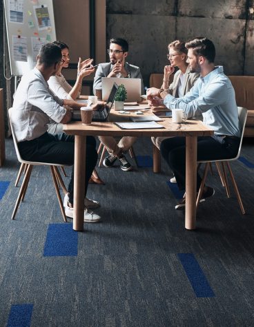 Confident and successful team. Group of young modern people in smart casual wear discussing business while sitting in the creative office